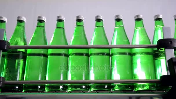 зелені пляшки для мінеральної води рухаються вздовж автоматичної виробничої лінії
. - Кадри, відео