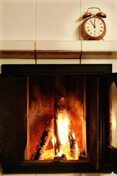 Fireplace and old-fashioned copper alarm clock on the mantelshe - Photo, Image
