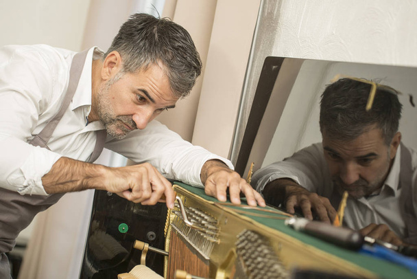 Technician tuning a upright piano using lever and tools - Foto, imagen