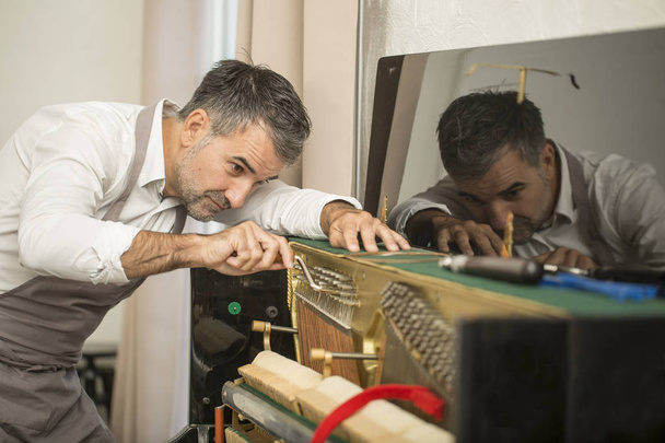 Technician tuning a upright piano using lever and tools - Fotoğraf, Görsel
