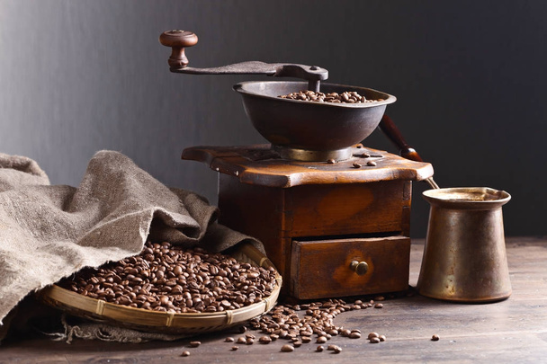 Старая кофемолка и жареные кофейные зерна на деревянном столе
  - Фото, изображение