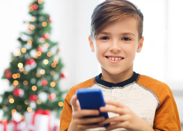 close up of happy boy with smartphone at christmas - Fotó, kép