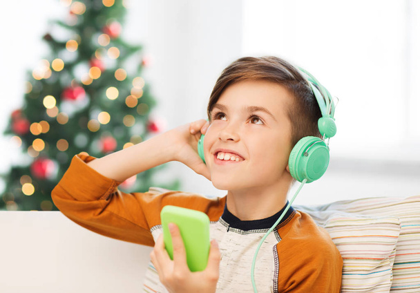 boy with smartphone and headphones at christmas - Fotoğraf, Görsel