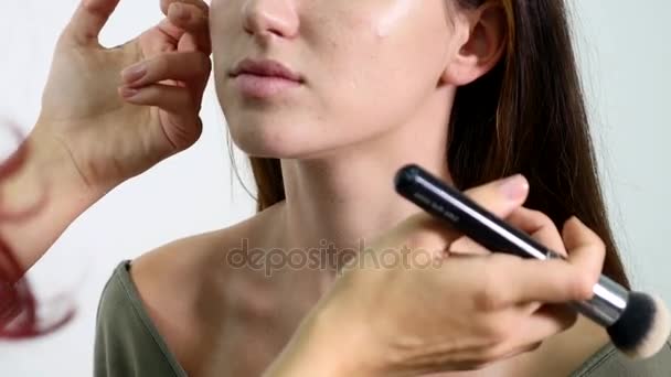 Makeup artist applying liquid tonal foundation on girls neck in white make up room. Beauty and fashion concept - Video, Çekim