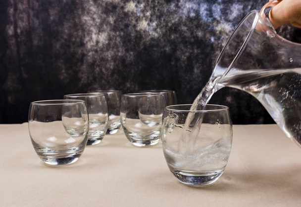 Wasser aus einem Krug in ein Glas gegossen. - Foto, Bild
