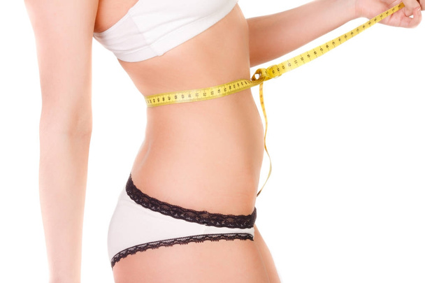 giovane donna con figura sottile che misura una dimensione del ventre con un nastro di misurazione, isolato
 - Foto, immagini