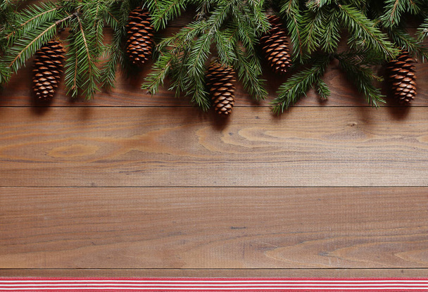 Fir-tree branches with cones on a wooden background - Фото, изображение