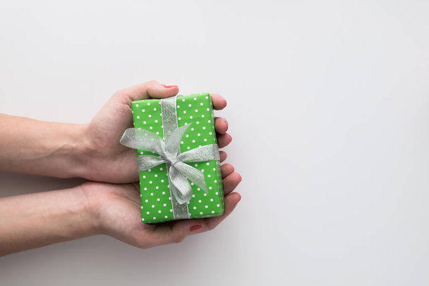 Vrouw handen met groene geschenkdoos geïsoleerd op een witte achtergrond. Bovenaanzicht, plat lag. Copyspace. - Foto, afbeelding