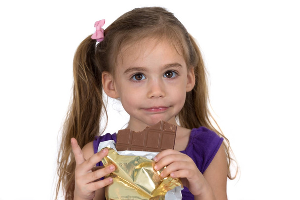 Dört yaşındaki kız çikolata yiyor ve bir jest yapar - Fotoğraf, Görsel