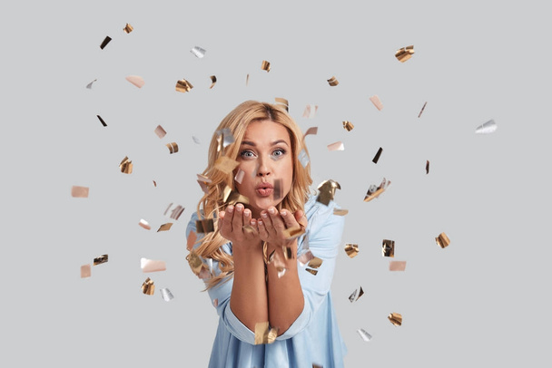 woman blowing confetti in studio - Foto, Imagen