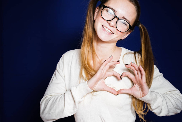 Girl student in glasses showing heart from fingers - Фото, изображение
