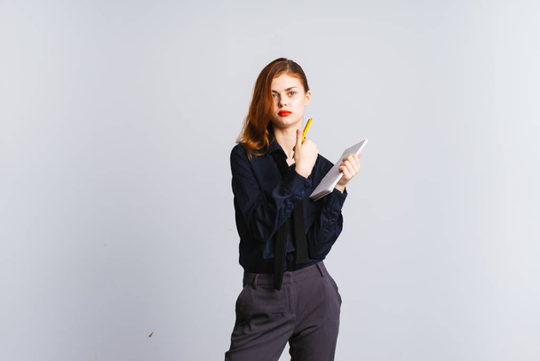 A girl with red hair and a black shirt posing against a white background - Foto, afbeelding