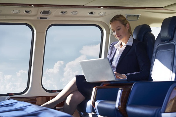 Businesswoman Working On Laptop In Helicopter Cabin During Fligh - Foto, immagini
