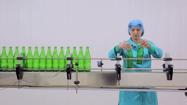 Línea de producción de agua. El empleado pone las botellas de vidrio en la línea de limpieza automática y llenado de botellas con agua
. - Metraje, vídeo