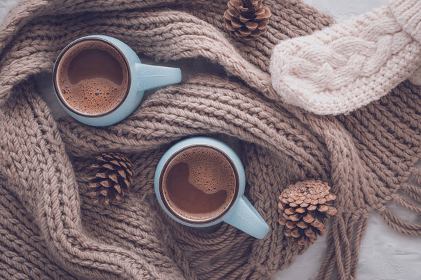 Christmas and New Year cozy holiday composition with scarf, mittens, pine cone, mugs with cocoa or chocolate on the gray concrete background. Flat lay, top view. - Φωτογραφία, εικόνα