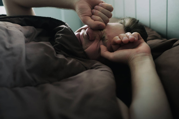 offensé homme caucasien allongé sur le lit et se couvrir avec une couverture. Il va pleurer.
. - Photo, image
