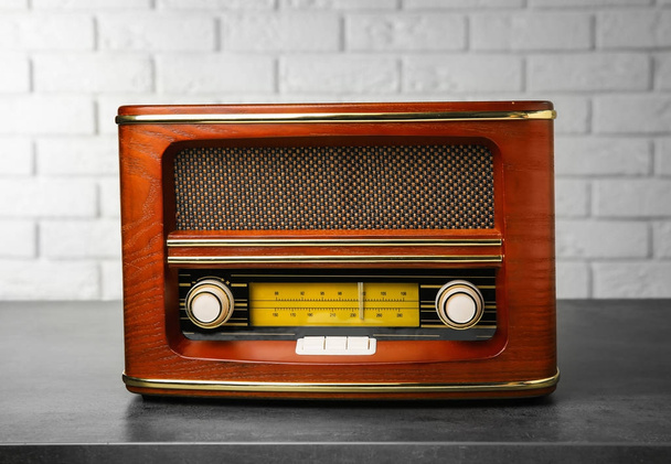 Retro radio on table near brick wall - Fotoğraf, Görsel