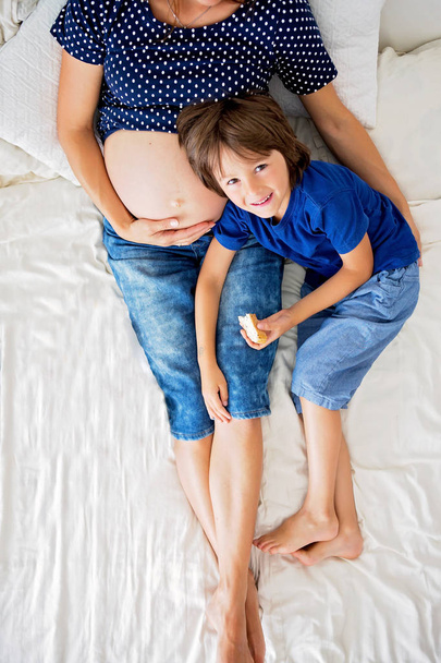 Young pregnant woman and her child, lying in bed - Foto, imagen