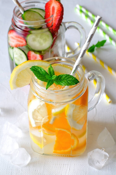 Summer refreshing iced drinks with orange, lemon, cucumber and strawberry on white background - Фото, изображение