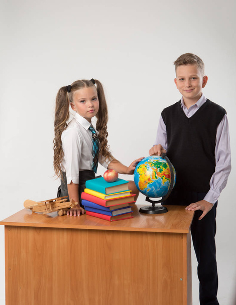 Happy boy and girl sit at a school desk, isolated on white background. - Foto, immagini