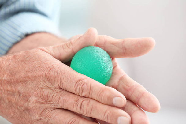 Hands of senior man doing exercise with rubber ball on blurred background, closeup - Foto, Bild