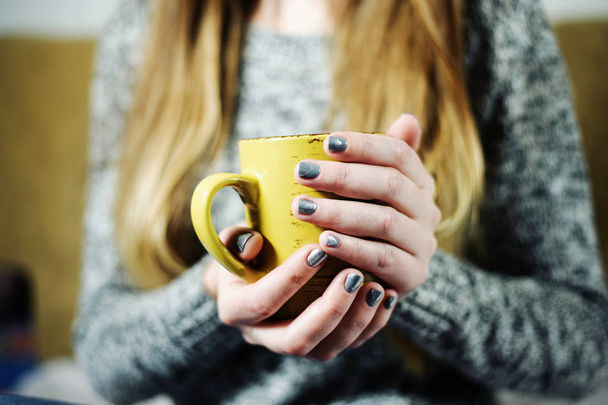 Chica está sosteniendo la taza de café o té en las manos con manicura de plata gris
 - Foto, imagen
