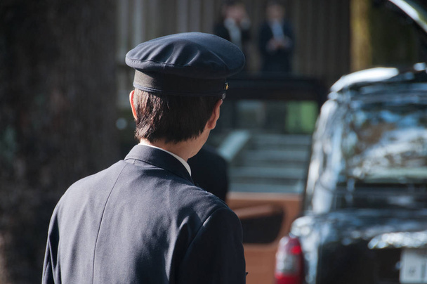Japanilainen taksinkuljettaja kääntyy vasemmalle hänen musta taksi
 - Valokuva, kuva