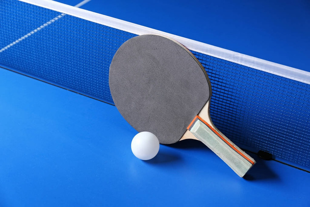 Ping pong racket and ball near net on table - Fotografie, Obrázek