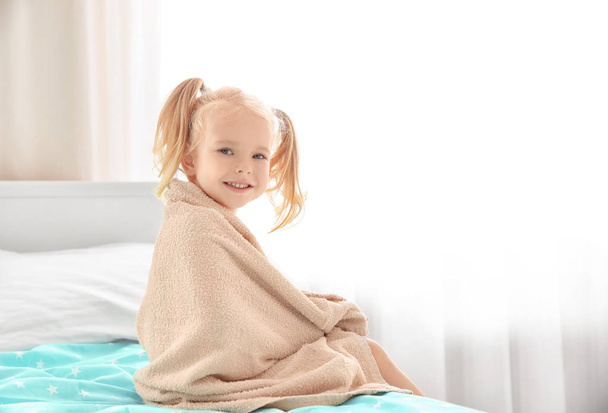 Cute little girl with towel on bed at home - Foto, Imagem
