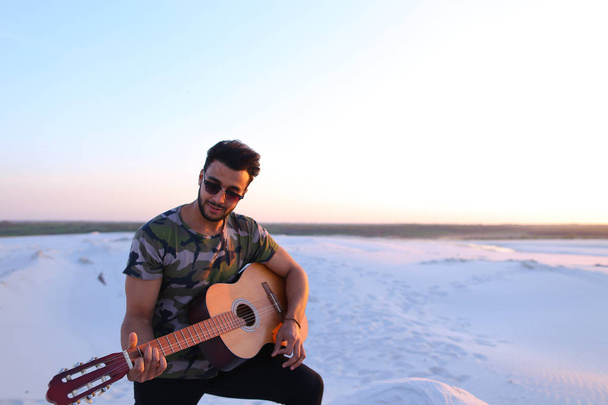 Retrato de jovem muçulmano que toca música na guitarra entre san
 - Foto, Imagem