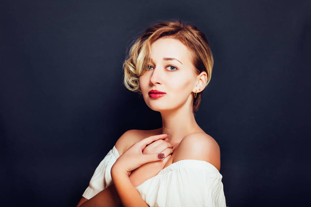 Blonde girl with a short stylish haircut on a dark background - Photo, Image