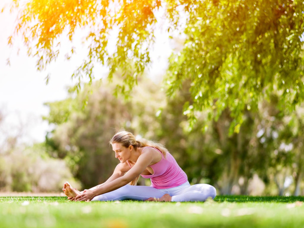 jonge vrouw doet yoga in het park - Foto, afbeelding