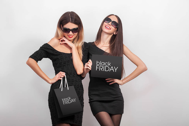 Schwarzer Freitag. Verkauf. zwei junge lächelnde Frauen zeigen Einkaufstasche - Foto, Bild