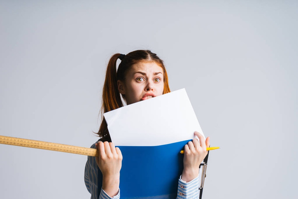 girl with two ponytails barely holding folders, isolated. folders cover the face - Photo, Image