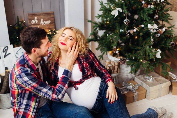 glückliche Schwangere schließt die Augen und genießt die Anwesenheit ihres Mannes in der Nähe der Neujahrslandschaft - Foto, Bild