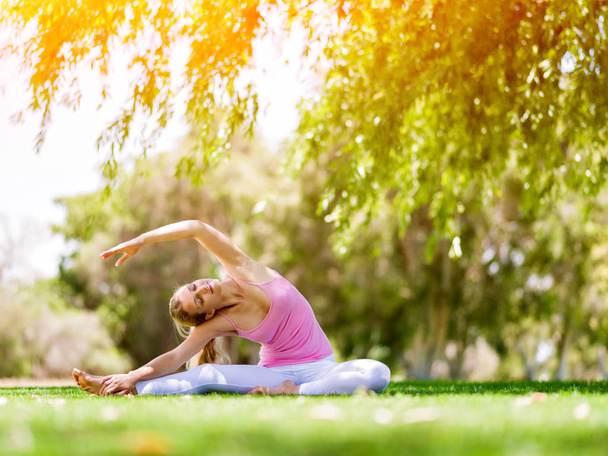 Young woman doing yoga in the park - 写真・画像