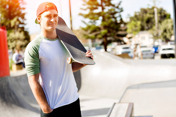 Хлопчик-підліток зі скейтбордом, що стоїть на відкритому повітрі
 - Фото, зображення