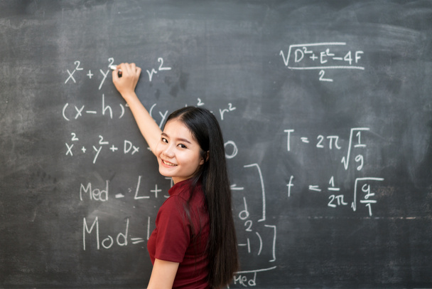 Beautiful Asian student writing on blackboard with chalk in clas - 写真・画像
