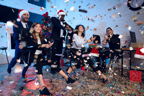 Office workers celebrate a new year in the office. They are entertaining and throwing confetti. They are having fun. - Photo, Image