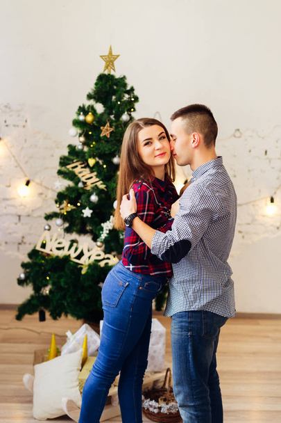 Lachen man met meisje omhelzen elkaar in de buurt van een kerstboom met geschenken - Foto, afbeelding