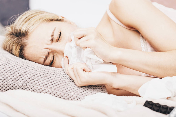 Больная женщина лежит в постели с высокой температурой. Холод, грипп, лихорадка и мигрень термометром и прикосновение ко лбу. В стрессе
.  - Фото, изображение