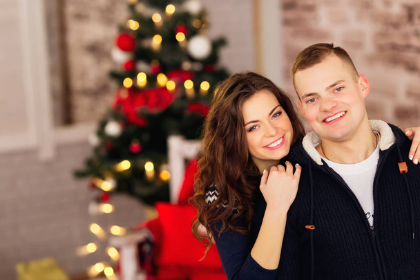 winter, mode, paar, Kerstmis en mensen concept - Glimlachende man en vrouw op vakantie lichten achtergrond knuffelen - Foto, afbeelding