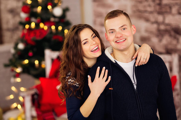 Laughing couple standing in a cozy room against blurred garlands - Foto, immagini