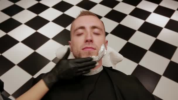 szczegół twarz człowieka rozprzestrzeniania pianki do golenia. Fryzjer, salon fryzjerski. - Materiał filmowy, wideo