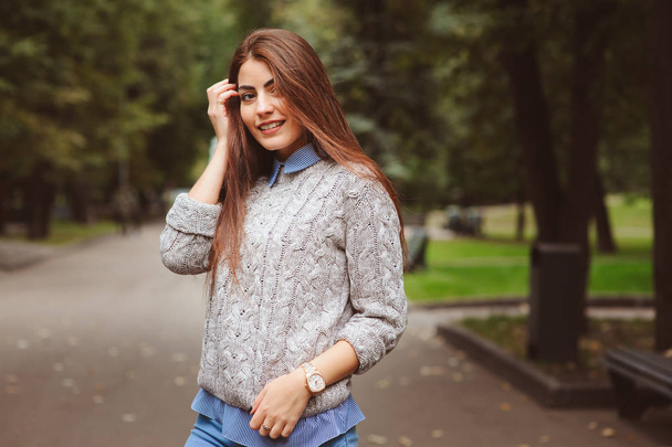 close up portrait of young beautiful happy girl with well conditioned long dark hair, walking in autumn city in warm knitted sweater - Фото, зображення