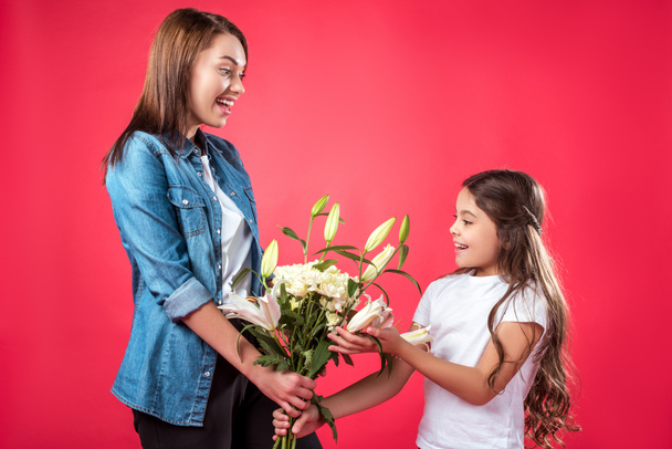 Mother presenting bouquet of flowers to daughter - 写真・画像