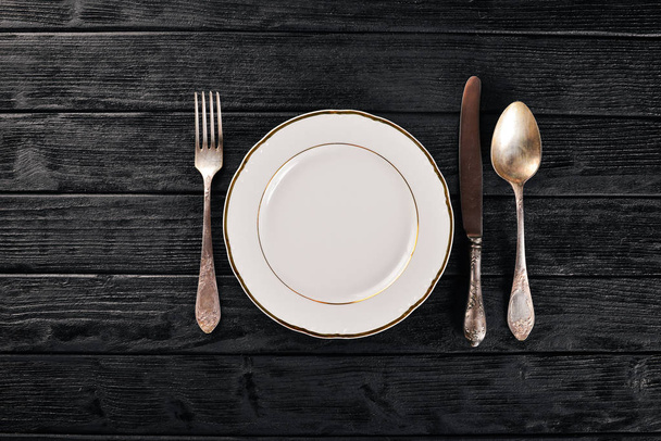 Plate and old cutlery. On a wooden background. Top view. Free space for text. - Фото, зображення