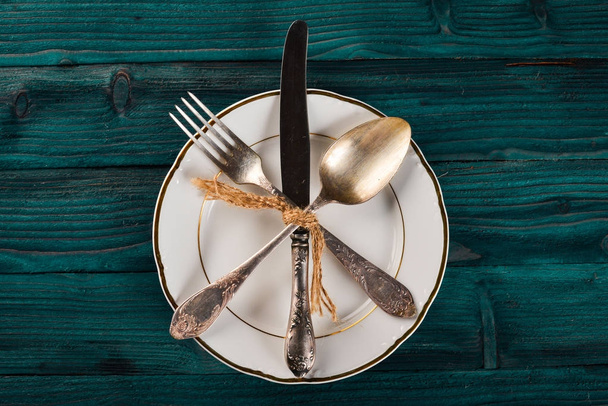 Plate and old cutlery. On a wooden background. Top view. Free space for text. - 写真・画像