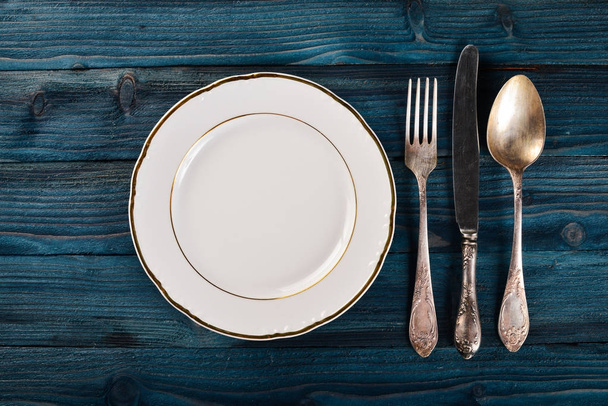 Plate and old cutlery. On a wooden background. Top view. Free space for text. - Photo, image