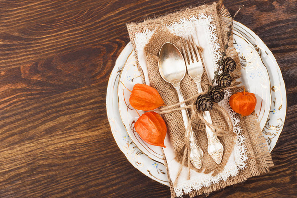 Tableware and silverware with autumn decorations on the wooden background - Фото, изображение